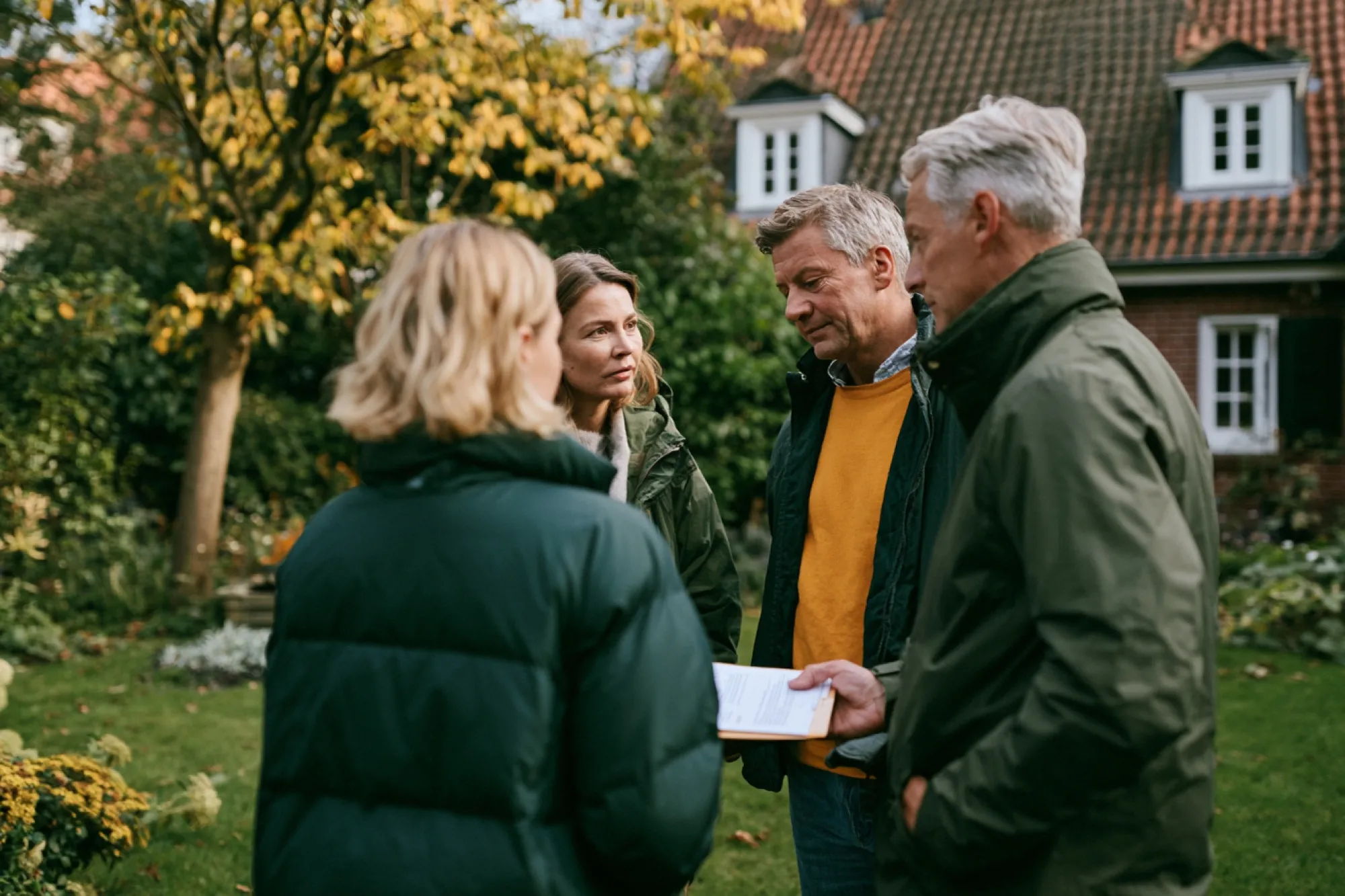Geschwister als Erbengemeinschaft besprechen im Garten, ob sie das geerbte Haus verkaufen